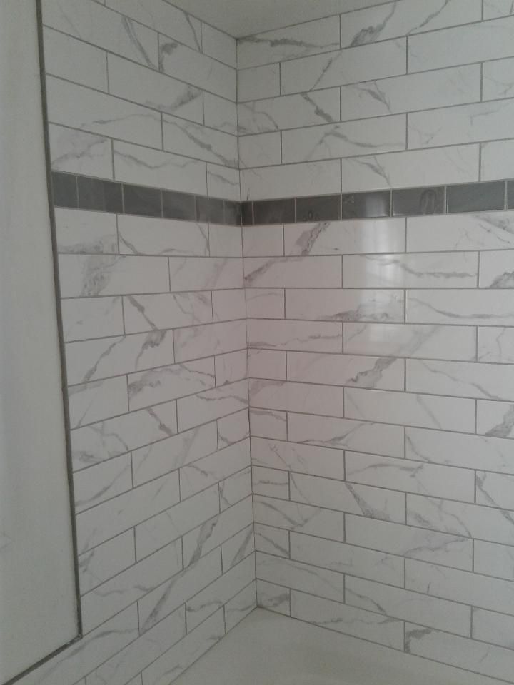 A bathroom with white tiles and a gray border.