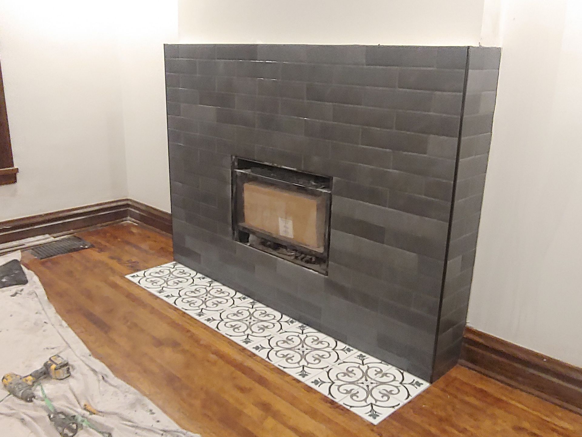 A fireplace is being remodeled in a living room with a wooden floor.