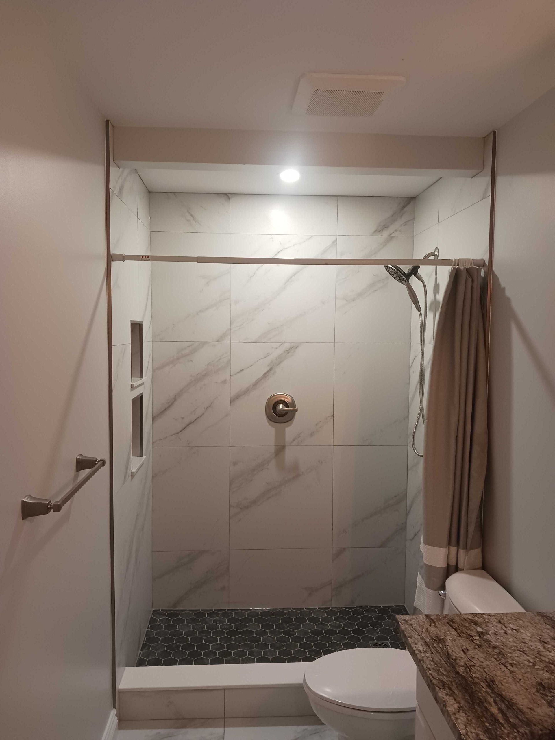 A bathroom with a walk in shower , toilet and sink.