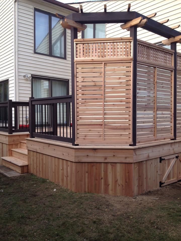 A wooden deck with a pergola and stairs in front of a house