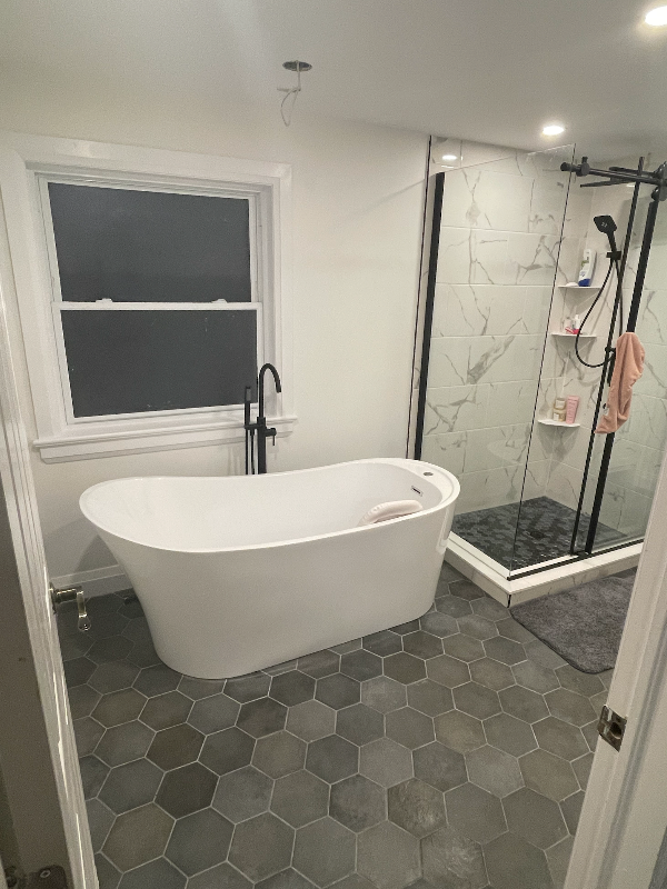 A bathroom with a tub , shower and window.
