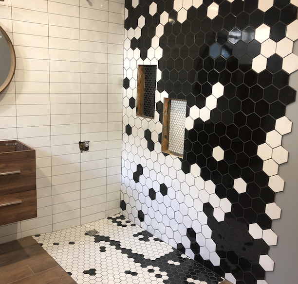 A bathroom with black and white tiles and a mirror