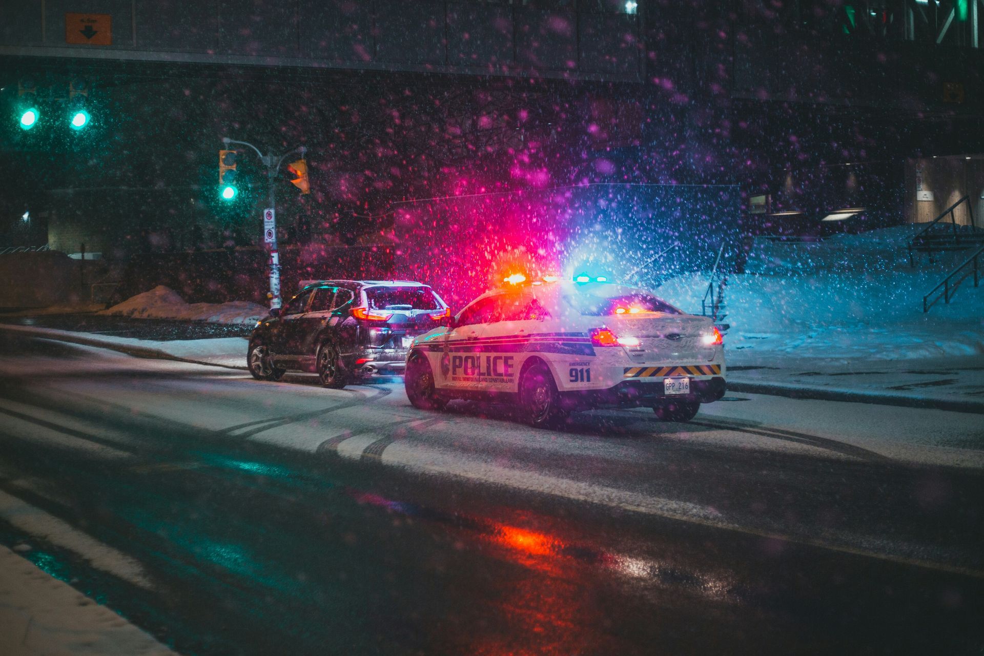 A police car is driving down a snowy street at night.