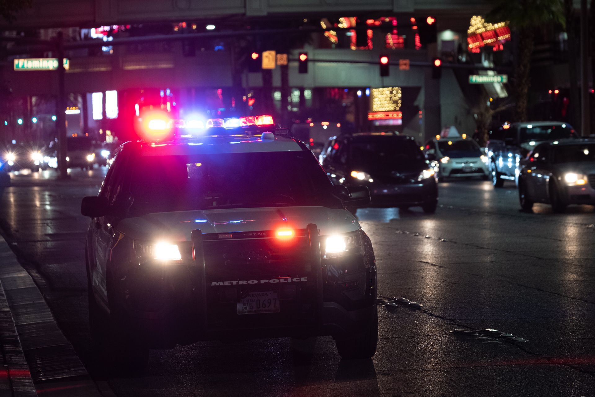 A police car is driving down a city street at night.