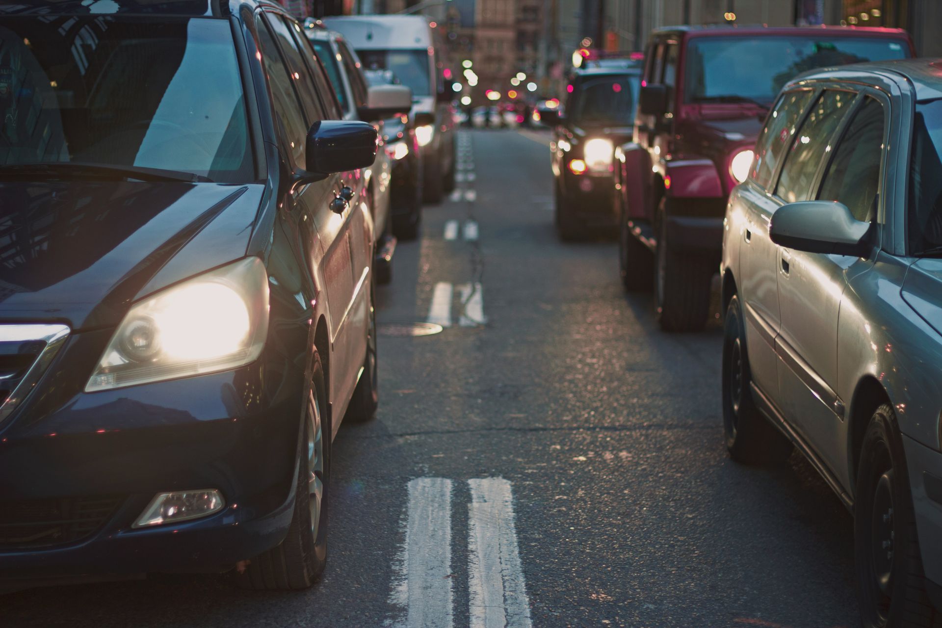 A row of cars are driving down a busy city street.