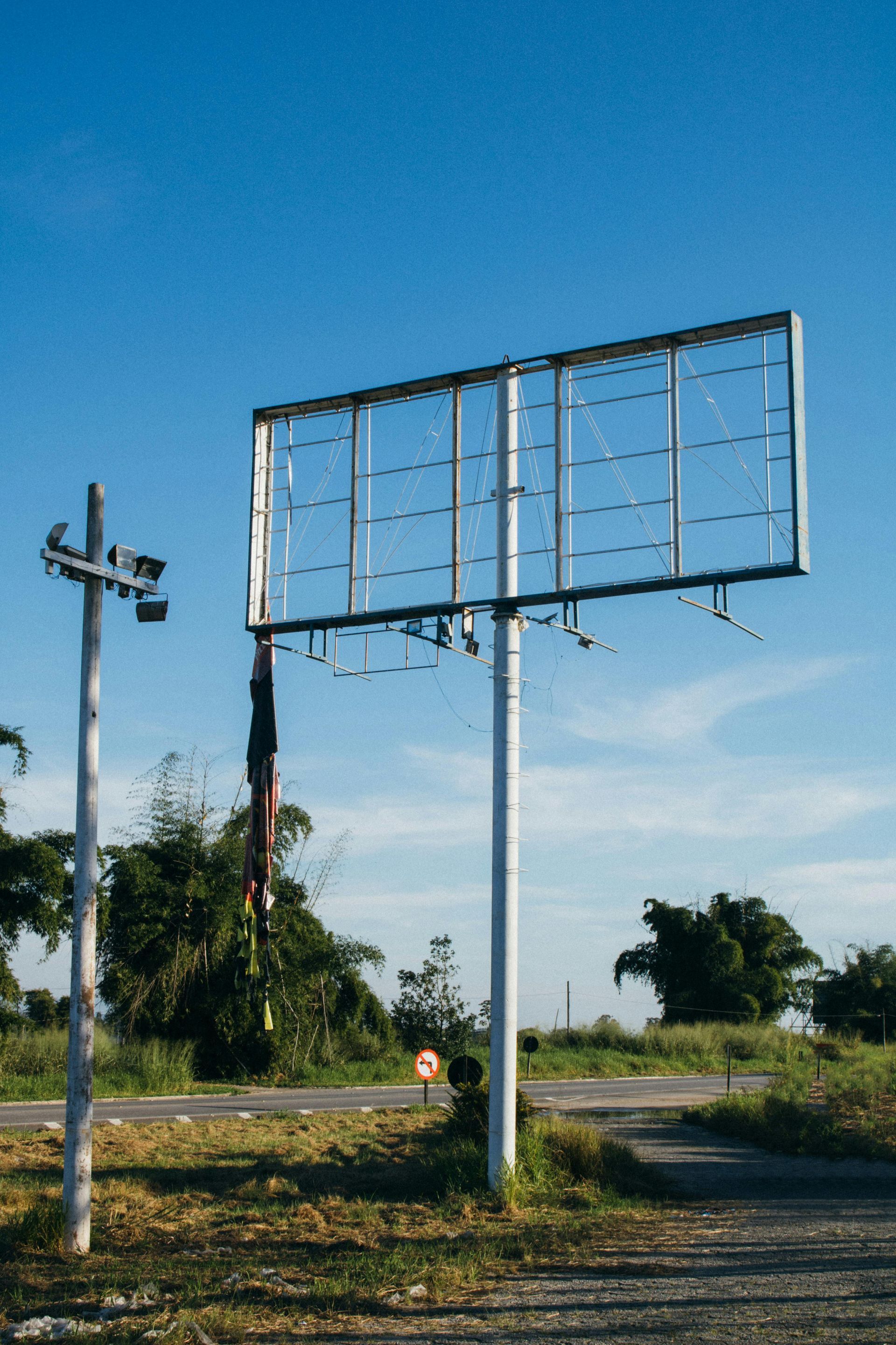 A large billboard is sitting in the middle of a field.