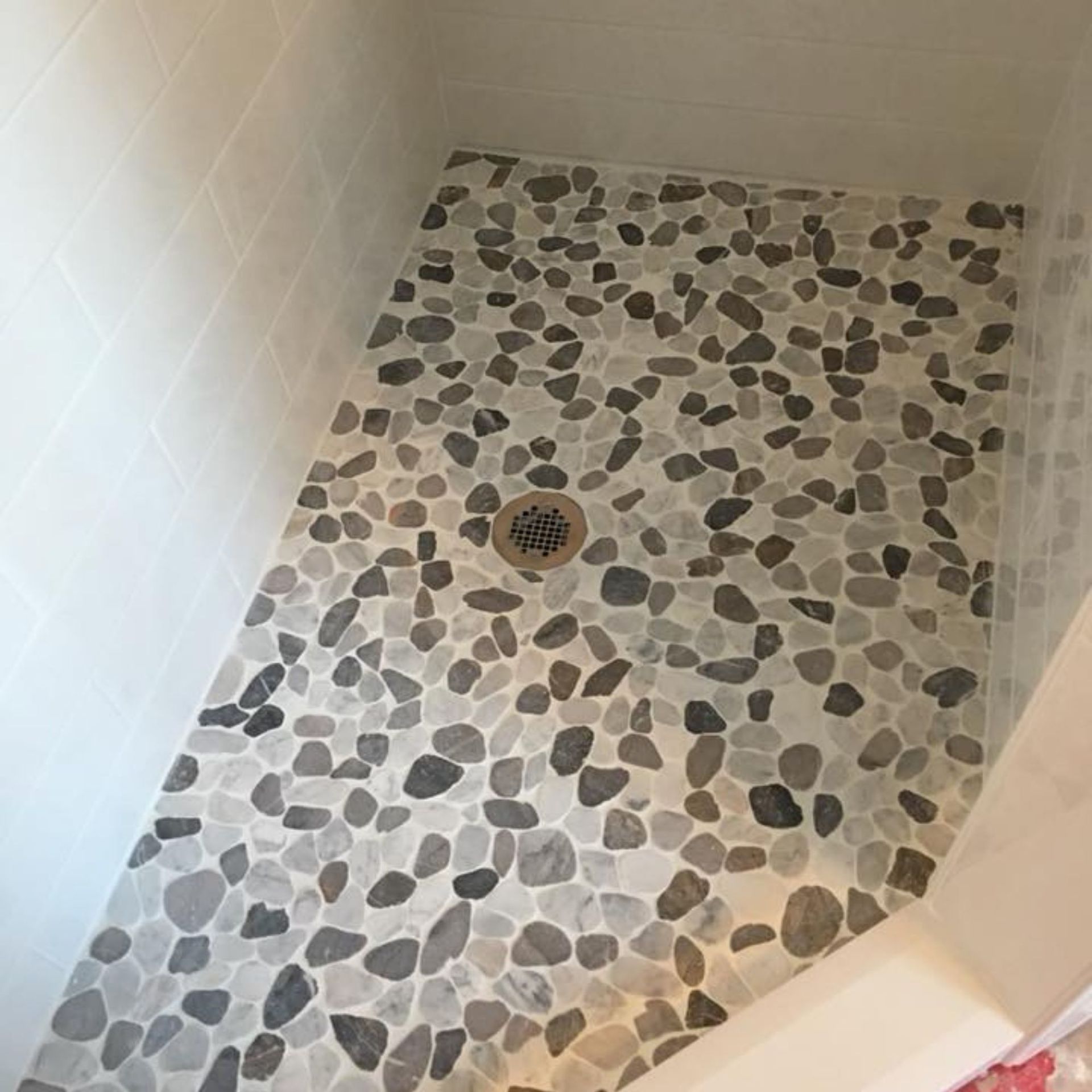 Masters Touch Roofing - A shower stall with a tiled floor and a drain.