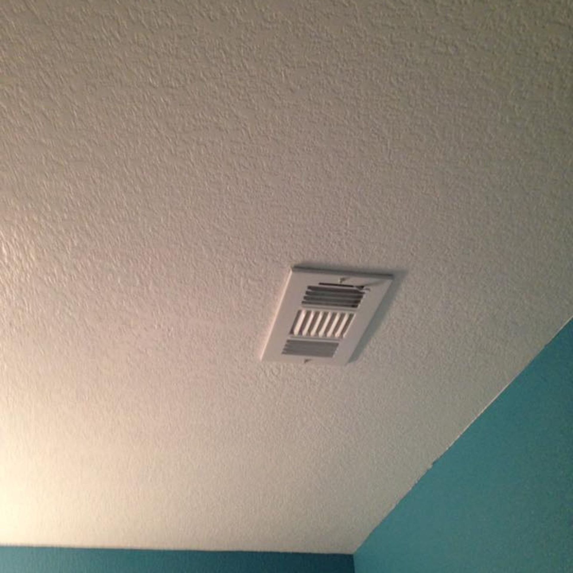 Masters Touch Roofing - There is a vent on the ceiling in a room with blue walls.