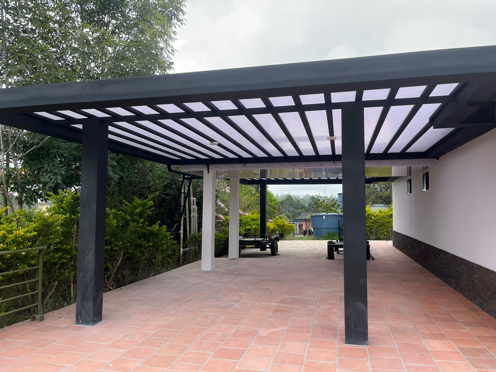 Una cochera con una pérgola y un banco debajo de ella.