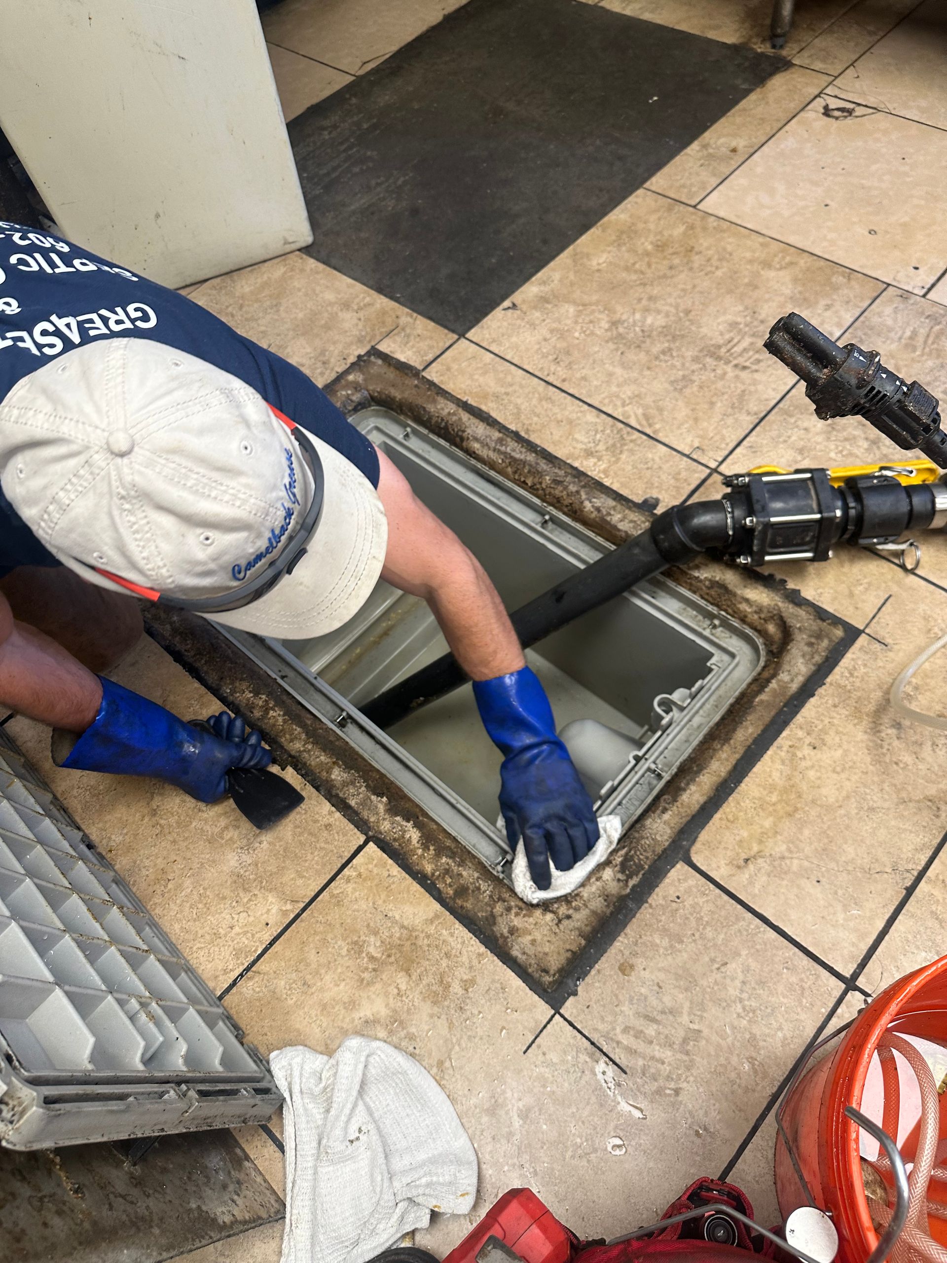 A man is cleaning a drain in a kitchen.