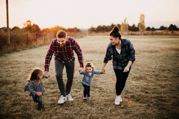 Family walking in a field holding hands at sunset.