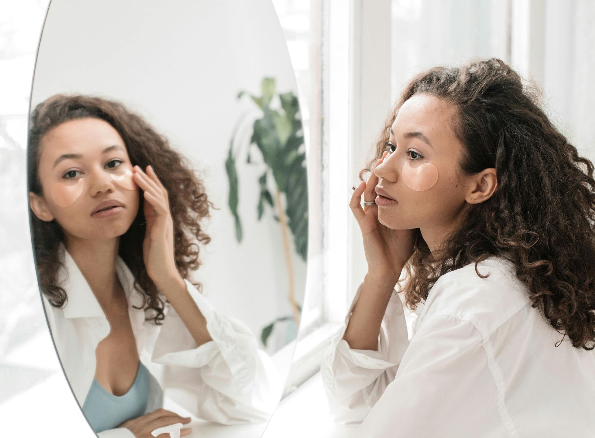 Une femme regarde son visage dans un miroir.