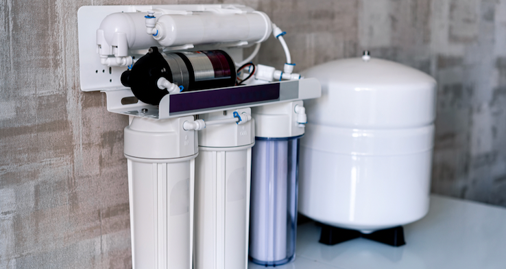 A water filter is sitting on a table next to a wall.