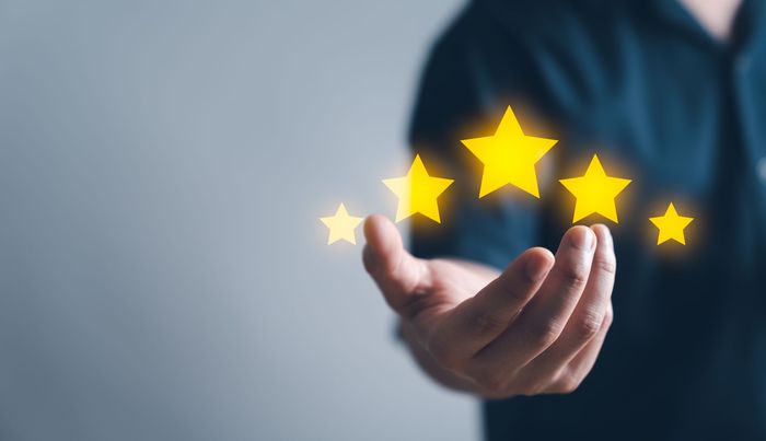 A man is holding four yellow stars in his hands.