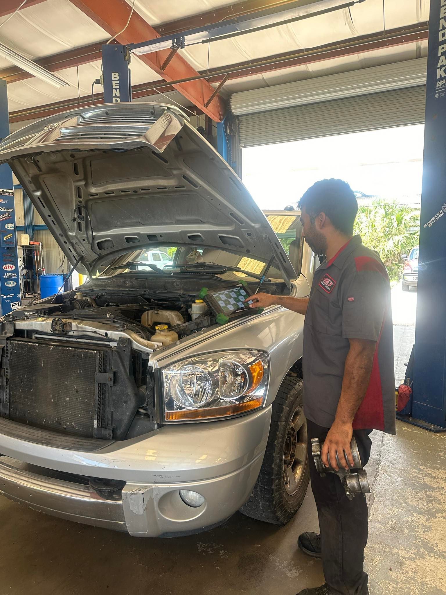 Mechanic inspects a silver pickup truck | Big 3 Diesel & Automotive Repair