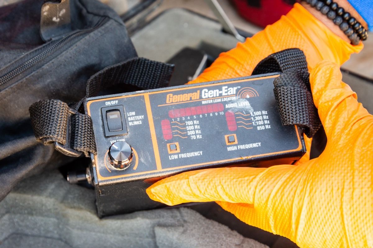 A person using a device to test a wooden floor in a home. 
