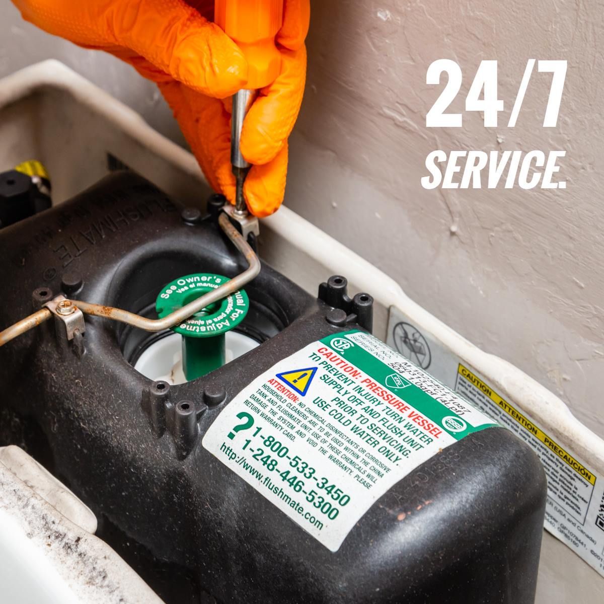 Orange-gloved hand repairing a toilet part. 24/7 service.