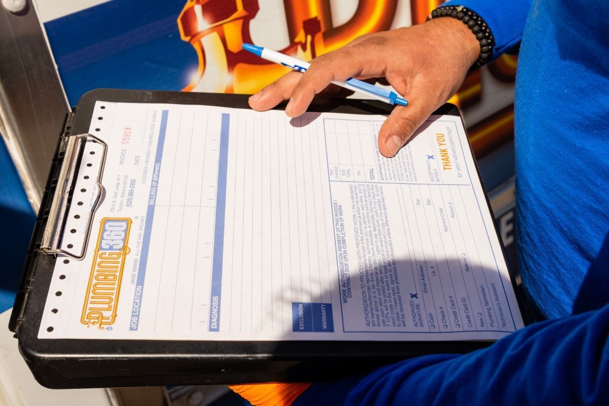 Person in blue shirt holding clipboard, writing on a form with a blue pen outdoors.