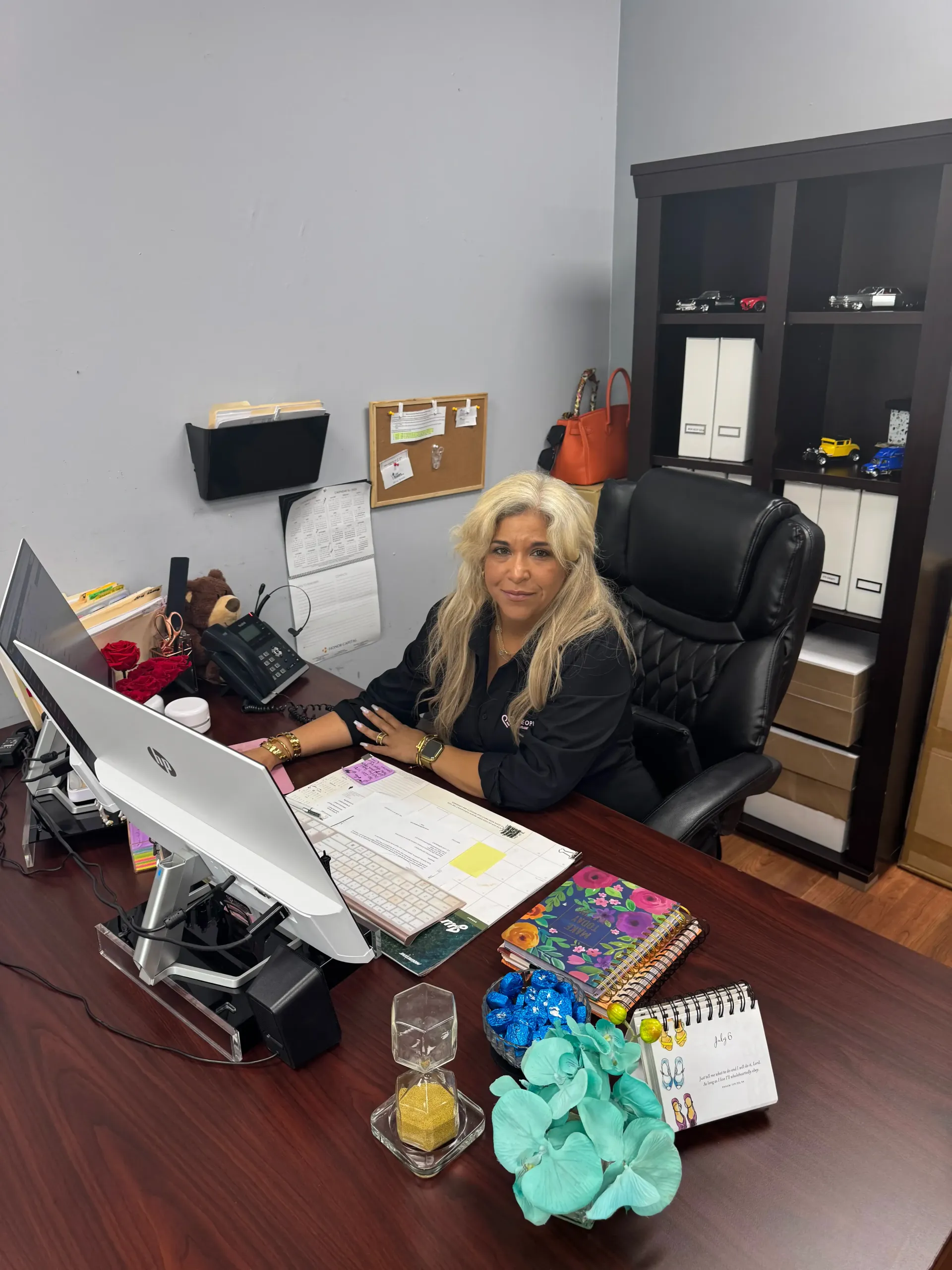 A woman is sitting at a desk in front of a computer.