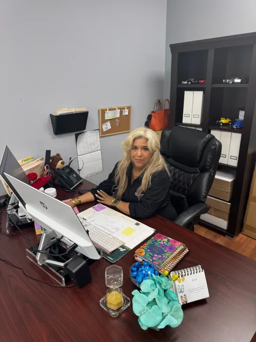 A woman is sitting at a desk in front of a computer.