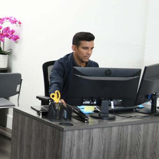 A man sits at a desk in front of an hp computer