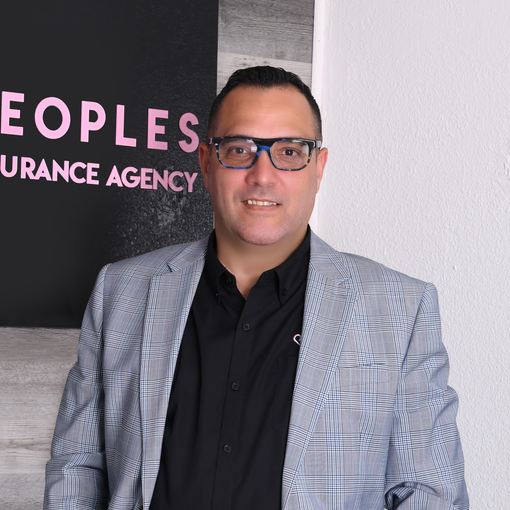 A man wearing glasses is standing in front of a sign that says peoples insurance agency