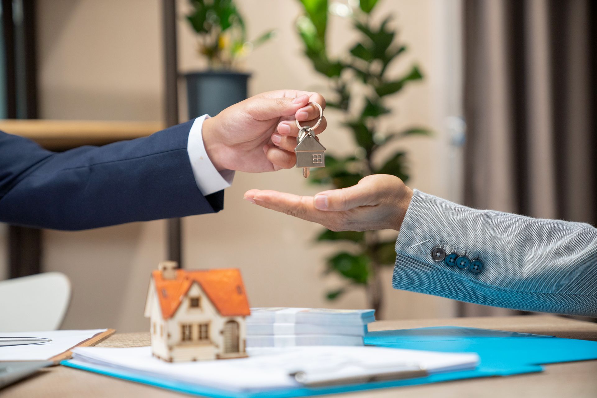 A man is handing a key to a woman in front of a model house.