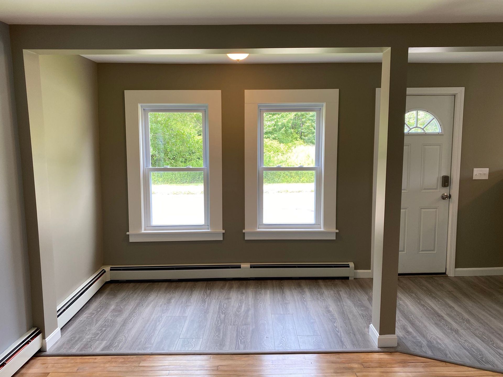 An empty room with two windows and a door