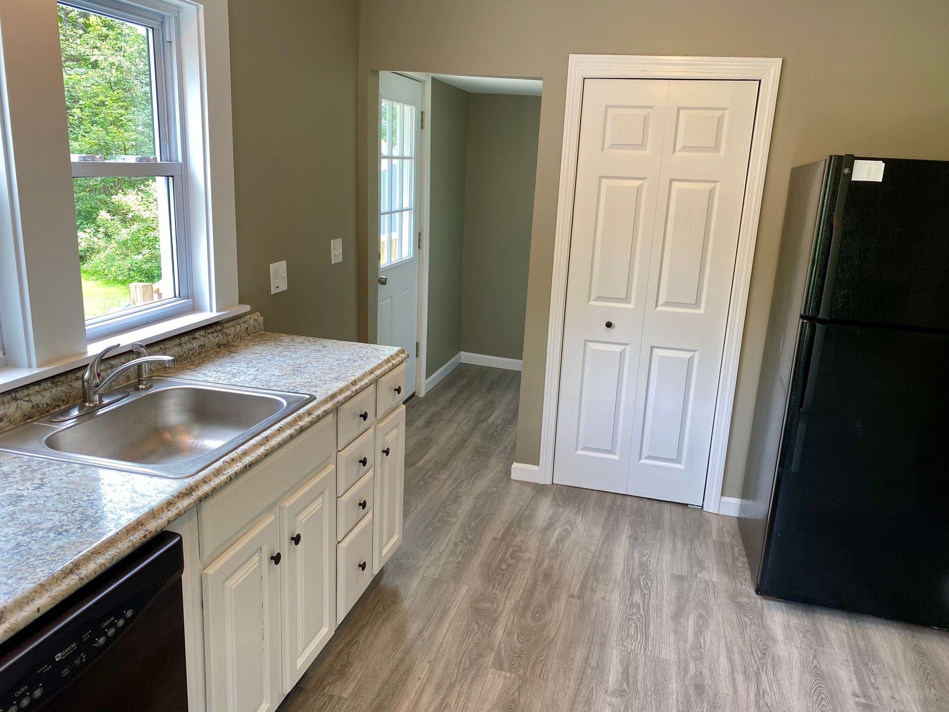 A kitchen with white cabinets and a black refrigerator
