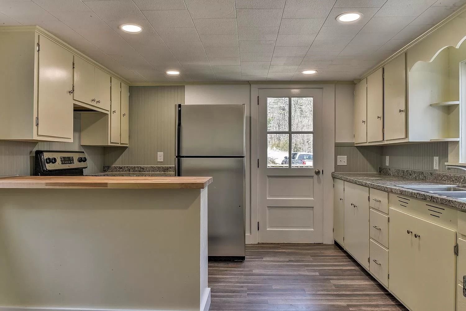 A kitchen with white cabinets and a stainless steel refrigerator