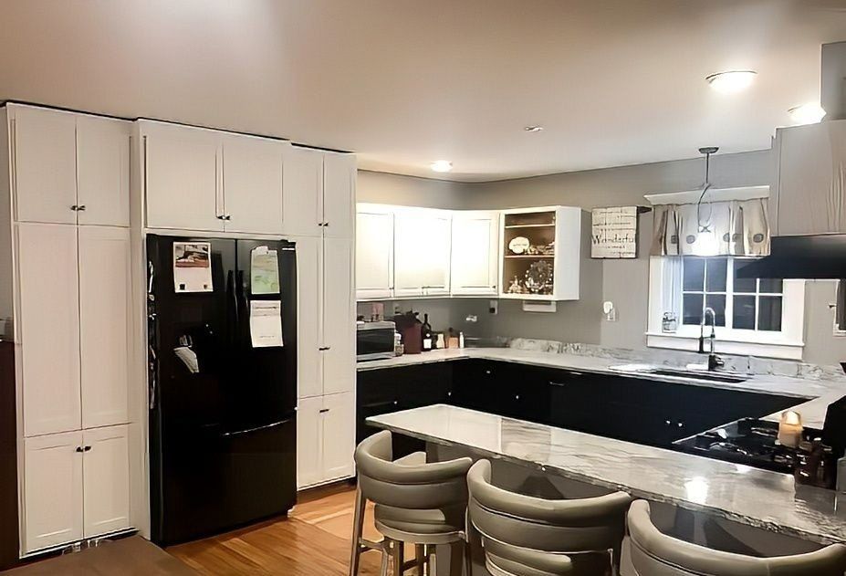 A kitchen with a black refrigerator and white cabinets