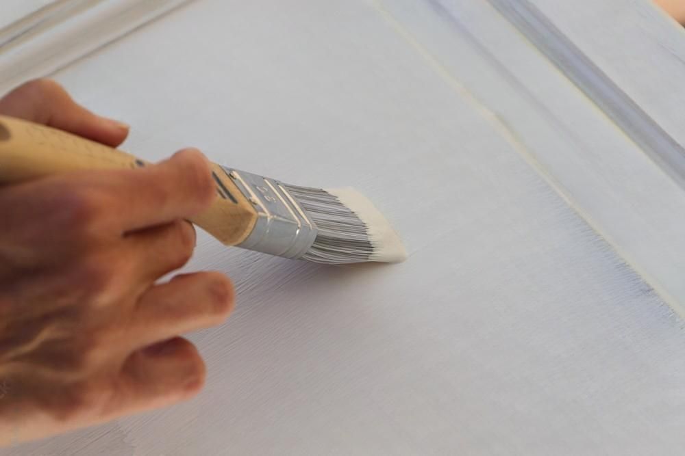 A person is painting a white door with a brush.