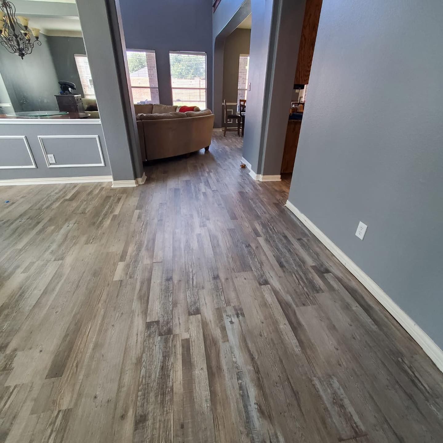 Hardwood-look flooring in a home with gray walls and visible living room and dining areas.