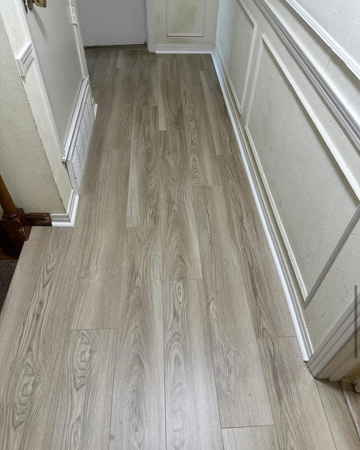 Light-colored wood-look flooring in a hallway with decorative molding on the walls.
