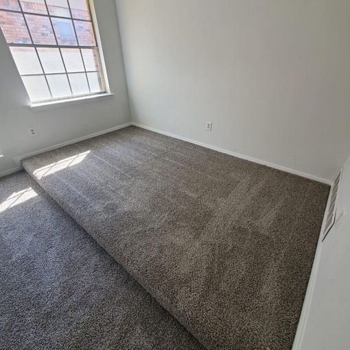 Empty bedroom with gray carpet, white walls, and a window.