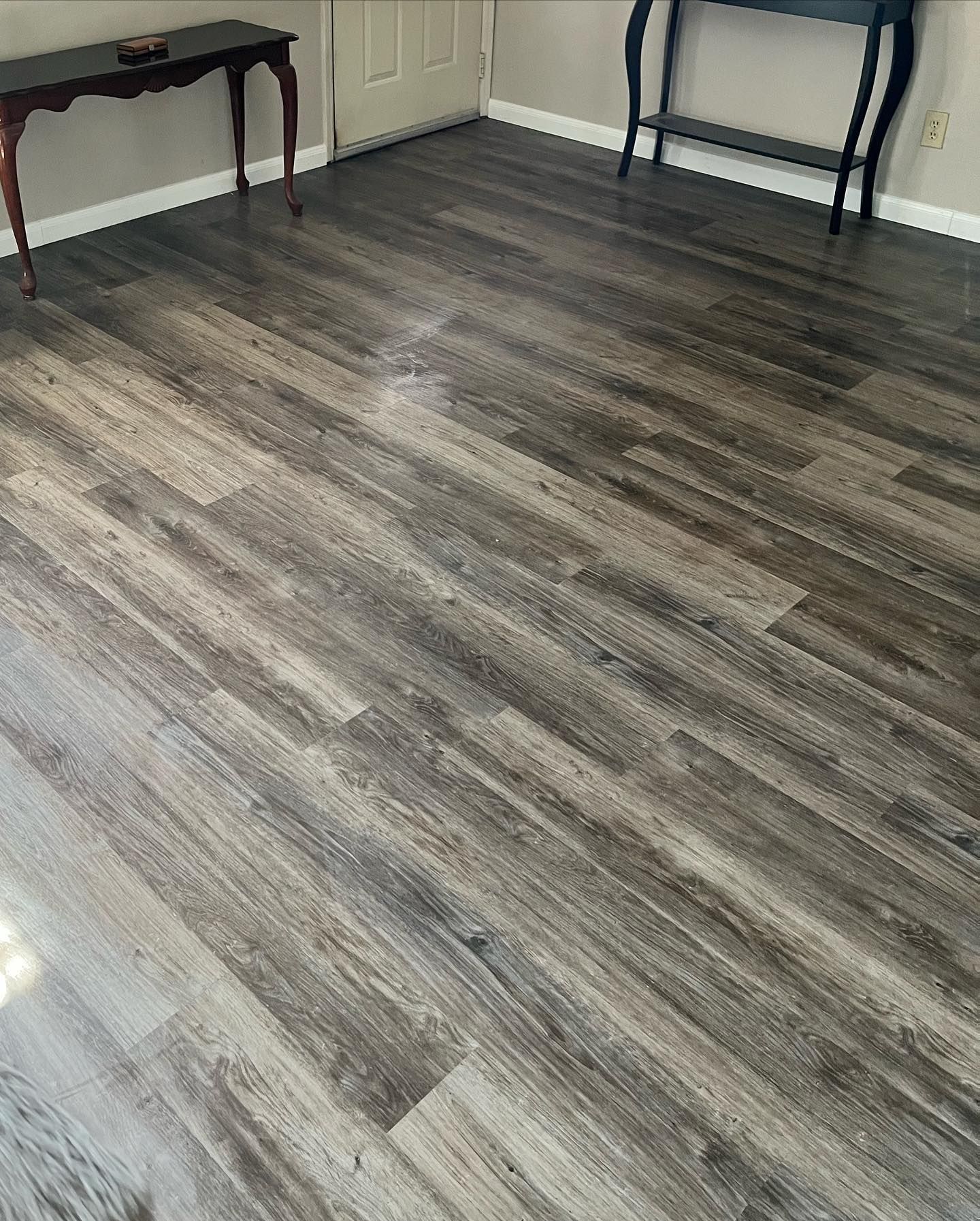 Dark wood-look flooring fills a room with two side tables against walls.