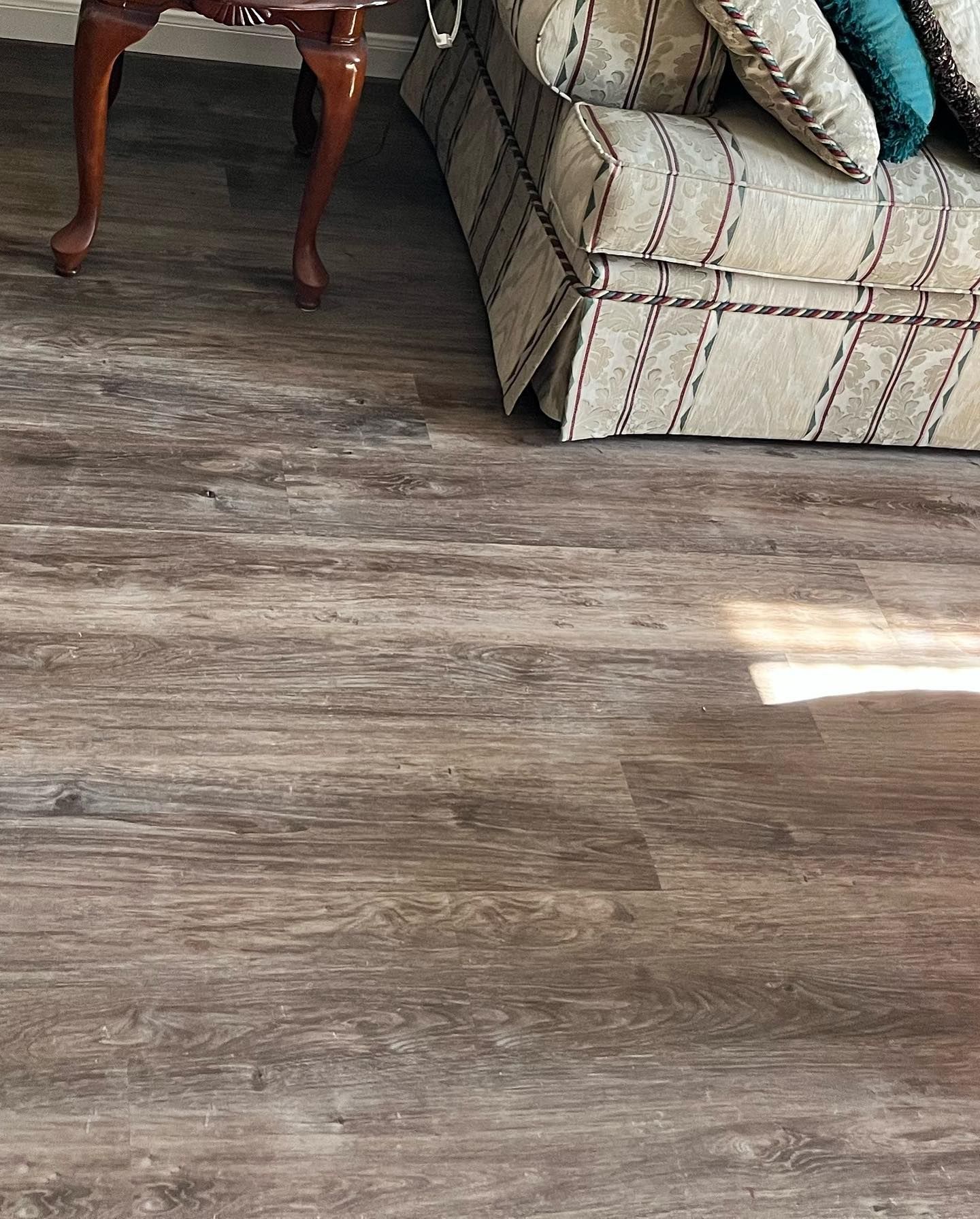 Wooden-look flooring near a patterned couch and a brown legged table.