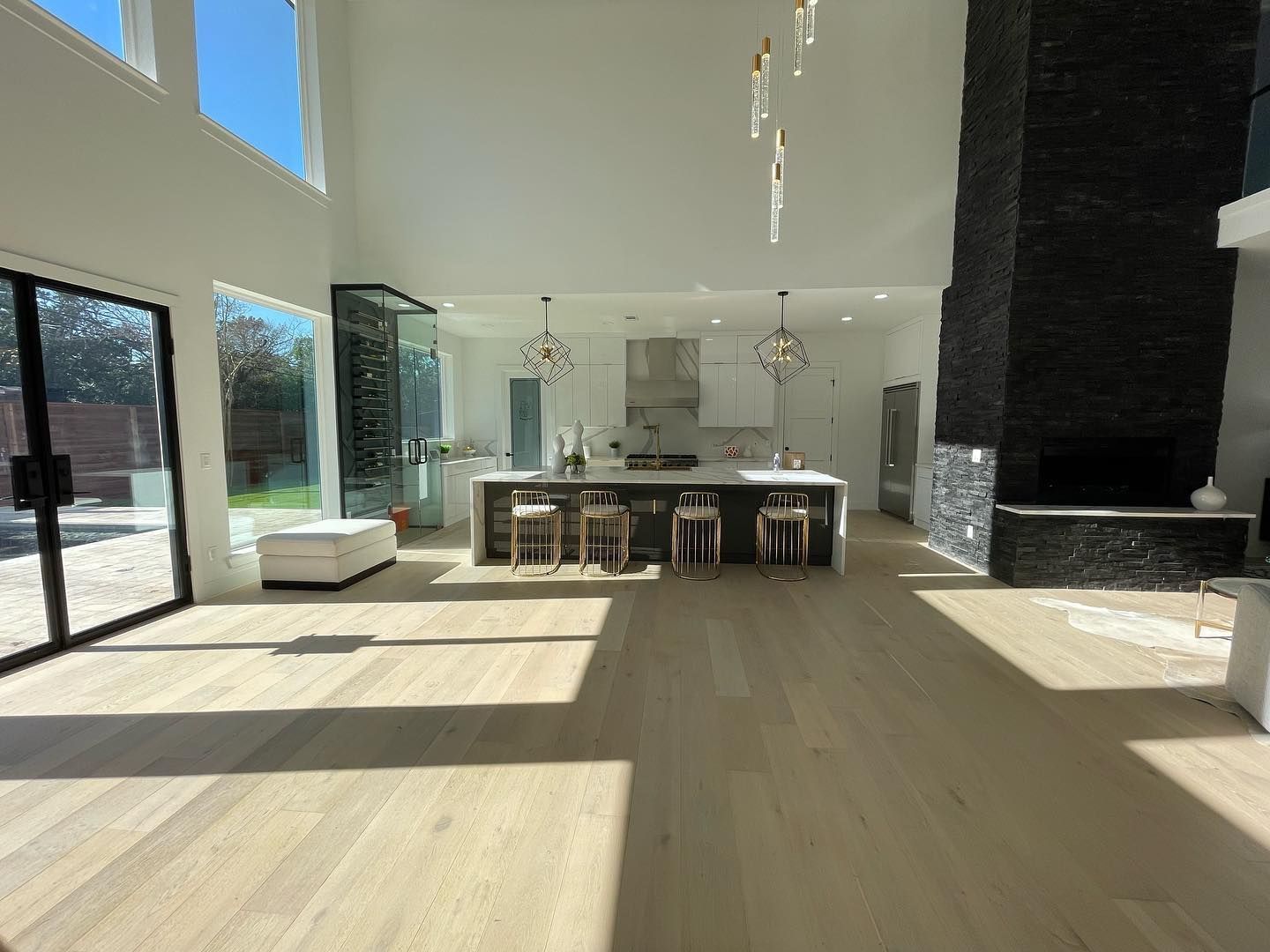 Spacious, modern kitchen with island, fireplace, and large windows letting in sunlight.