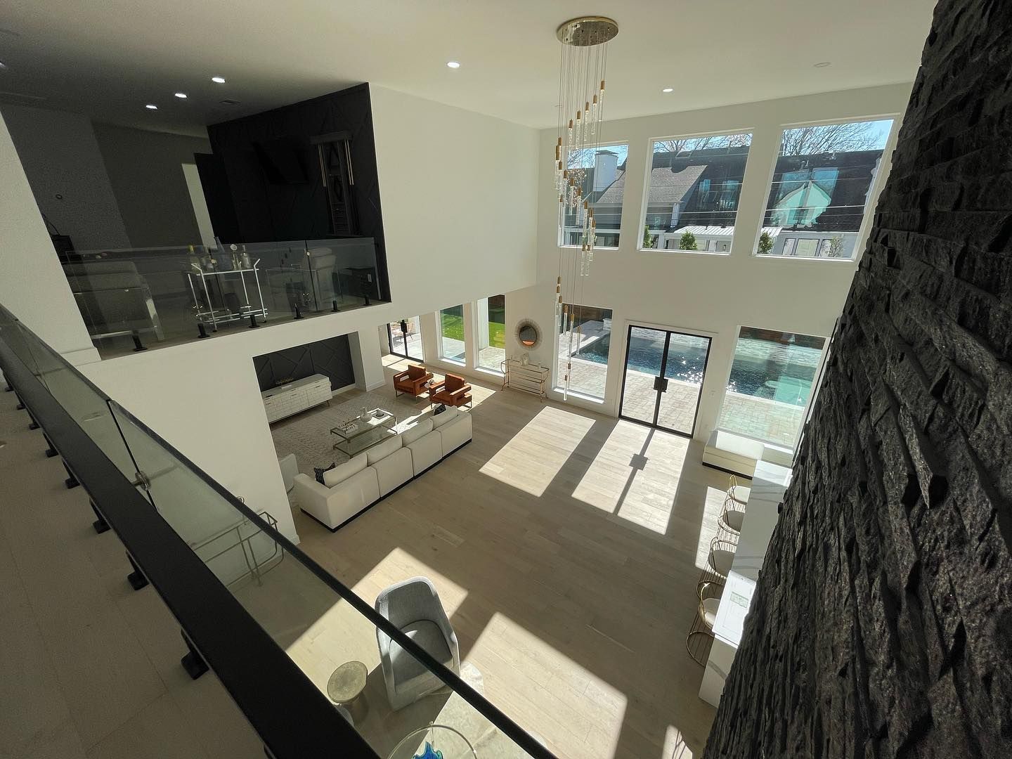 Modern two-story interior with a kitchen, large windows, and an open layout, viewed from a balcony.