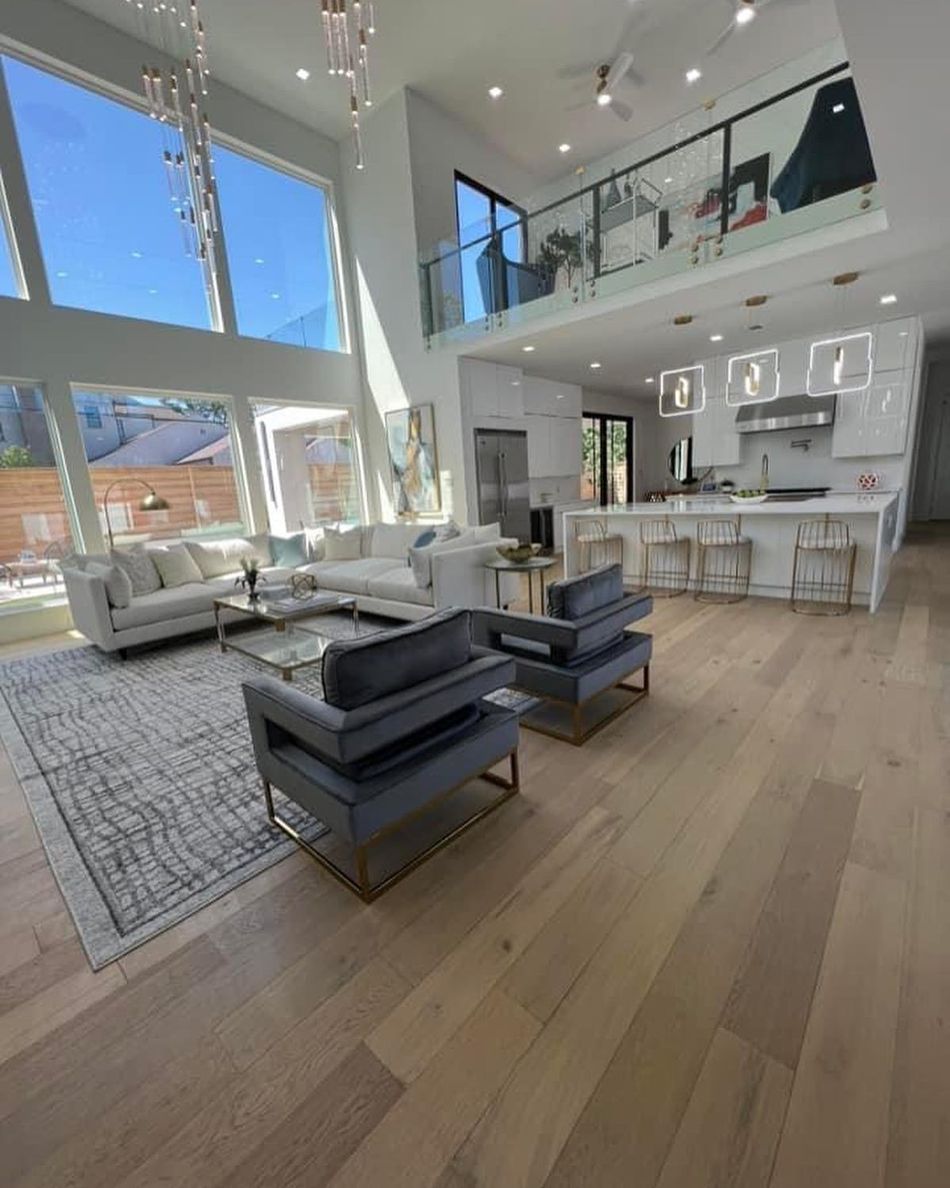 Modern open-concept living space with high ceilings, large windows, and a loft 
