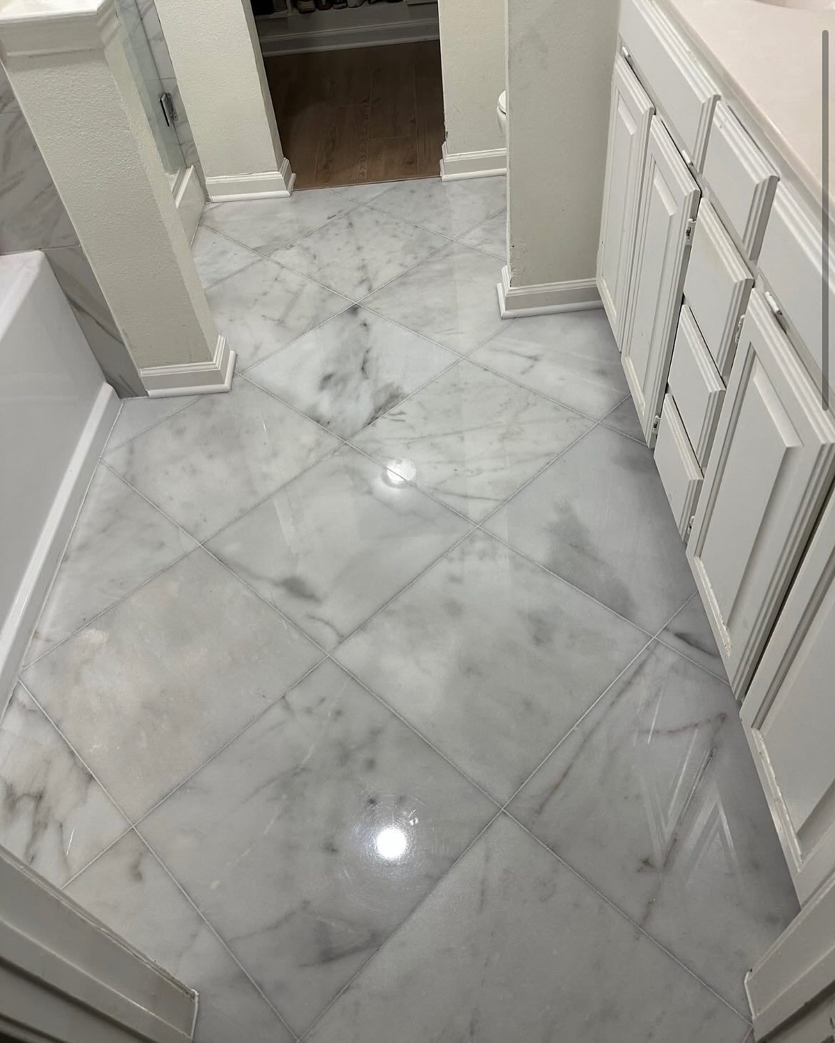 Bathroom floor with marble-like tiles in a diamond pattern. White cabinets and columns frame the space.