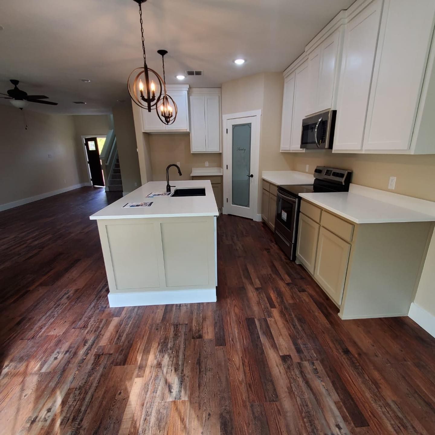 Kitchen with white cabinets, island, and dark wood floors; black appliances.