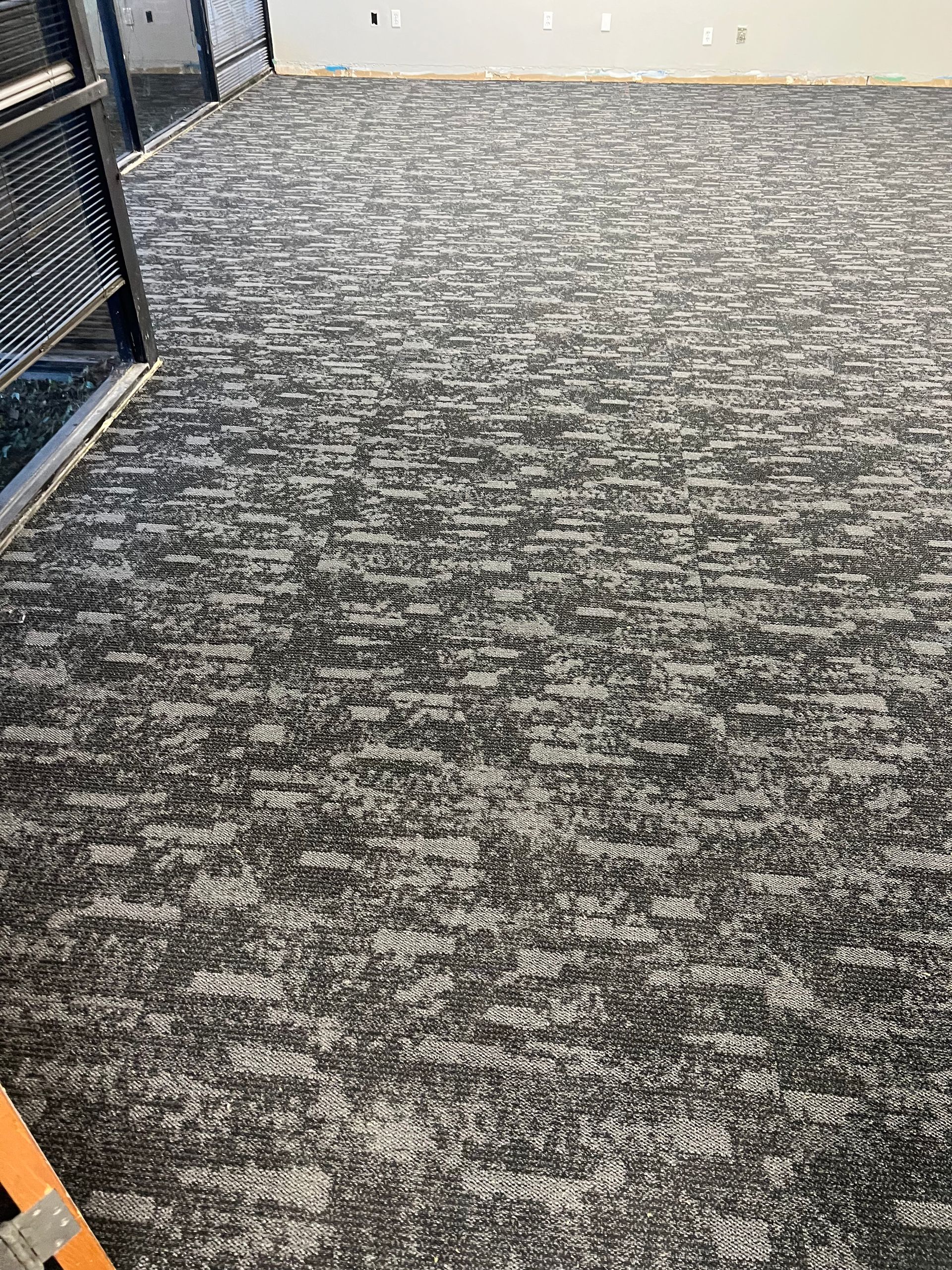 New commercial carpet with black, gray, and white mottled pattern, installed in a room.