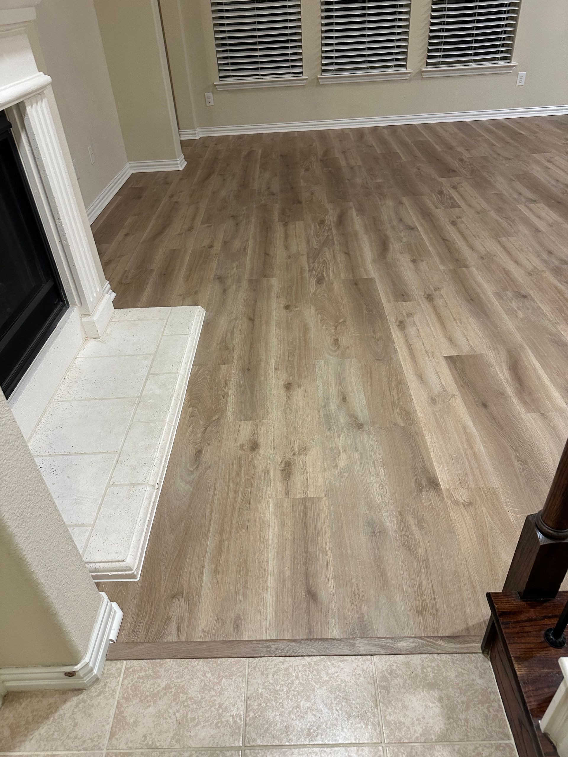 Living room with hardwood floors, fireplace, and windows with blinds.