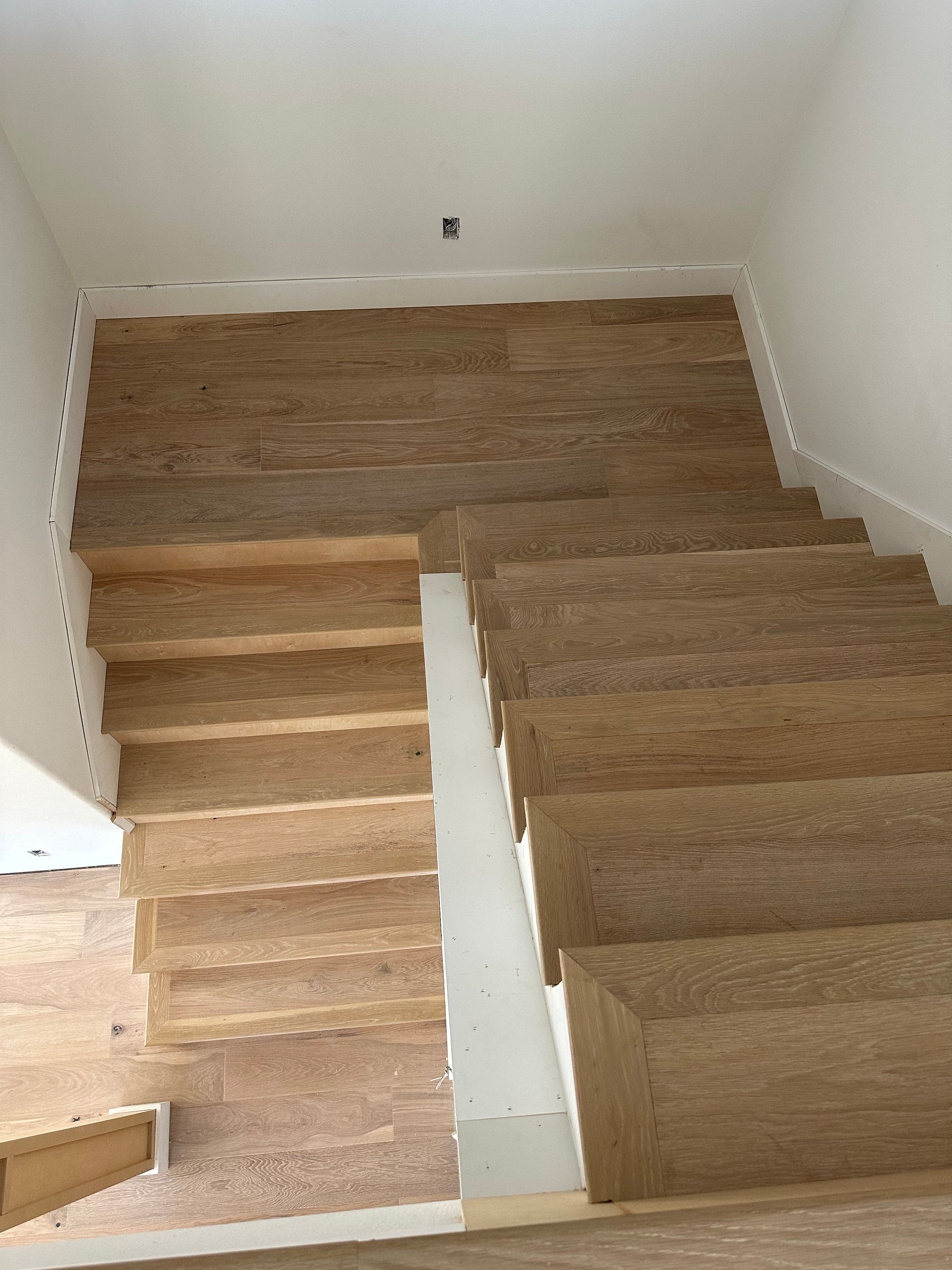 Wooden staircase with white trim, leading to a landing and upper level.