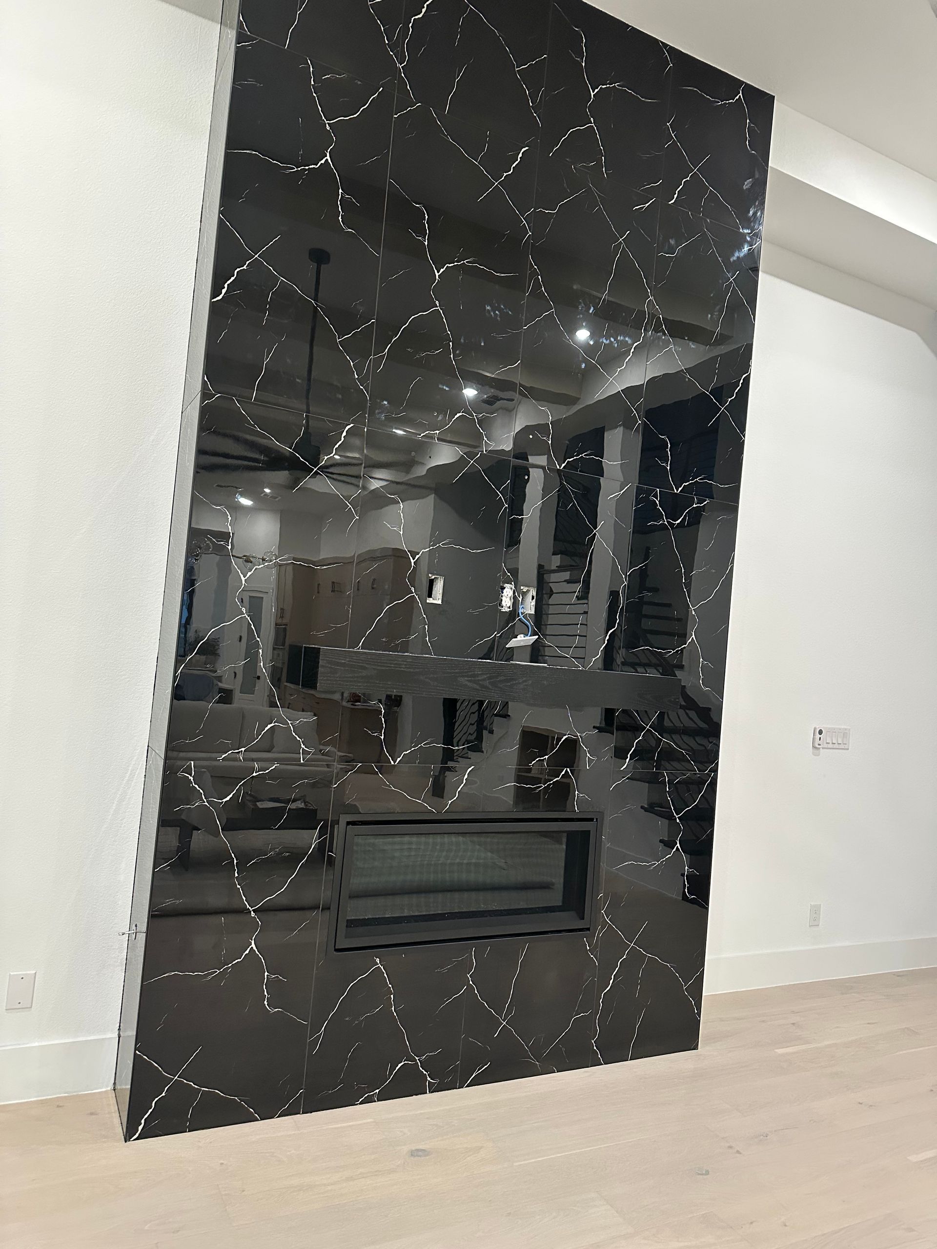 Black, patterned fireplace wall with a built-in fireplace in a modern home.