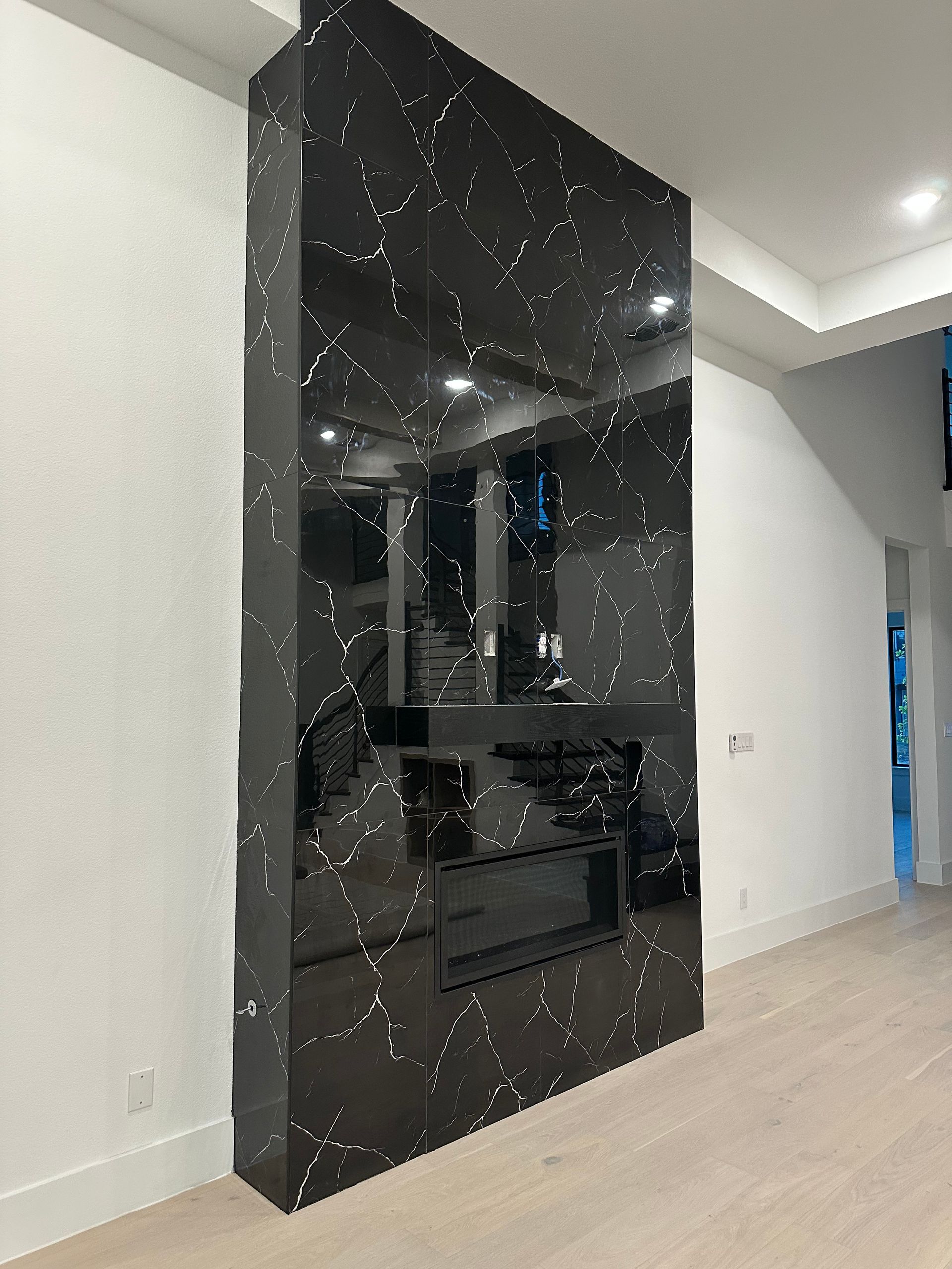 Black, starry-patterned fireplace in a modern white-walled room with light wood floors.