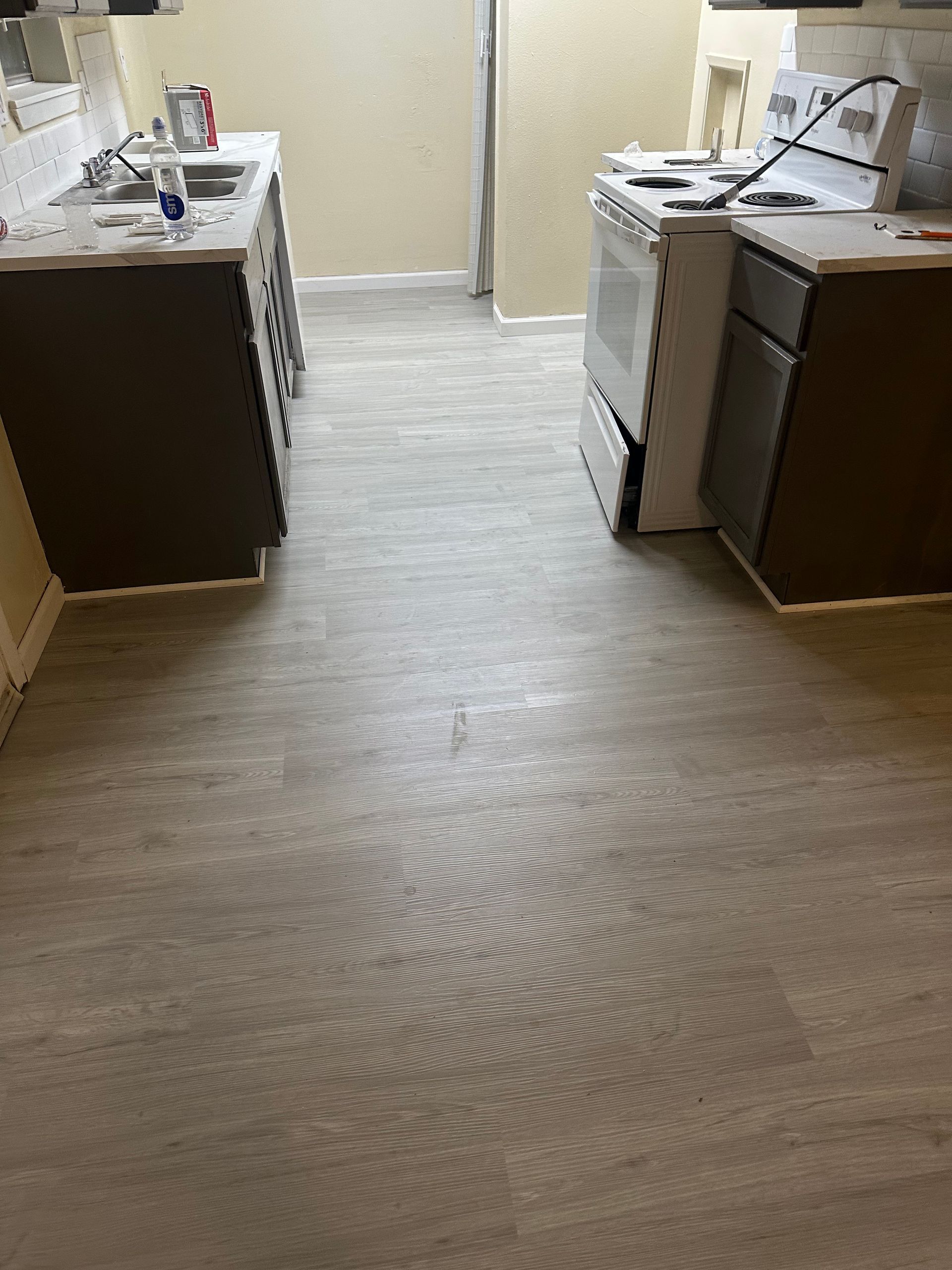 Kitchen with gray flooring, dark cabinets, and white appliances, undergoing renovation.