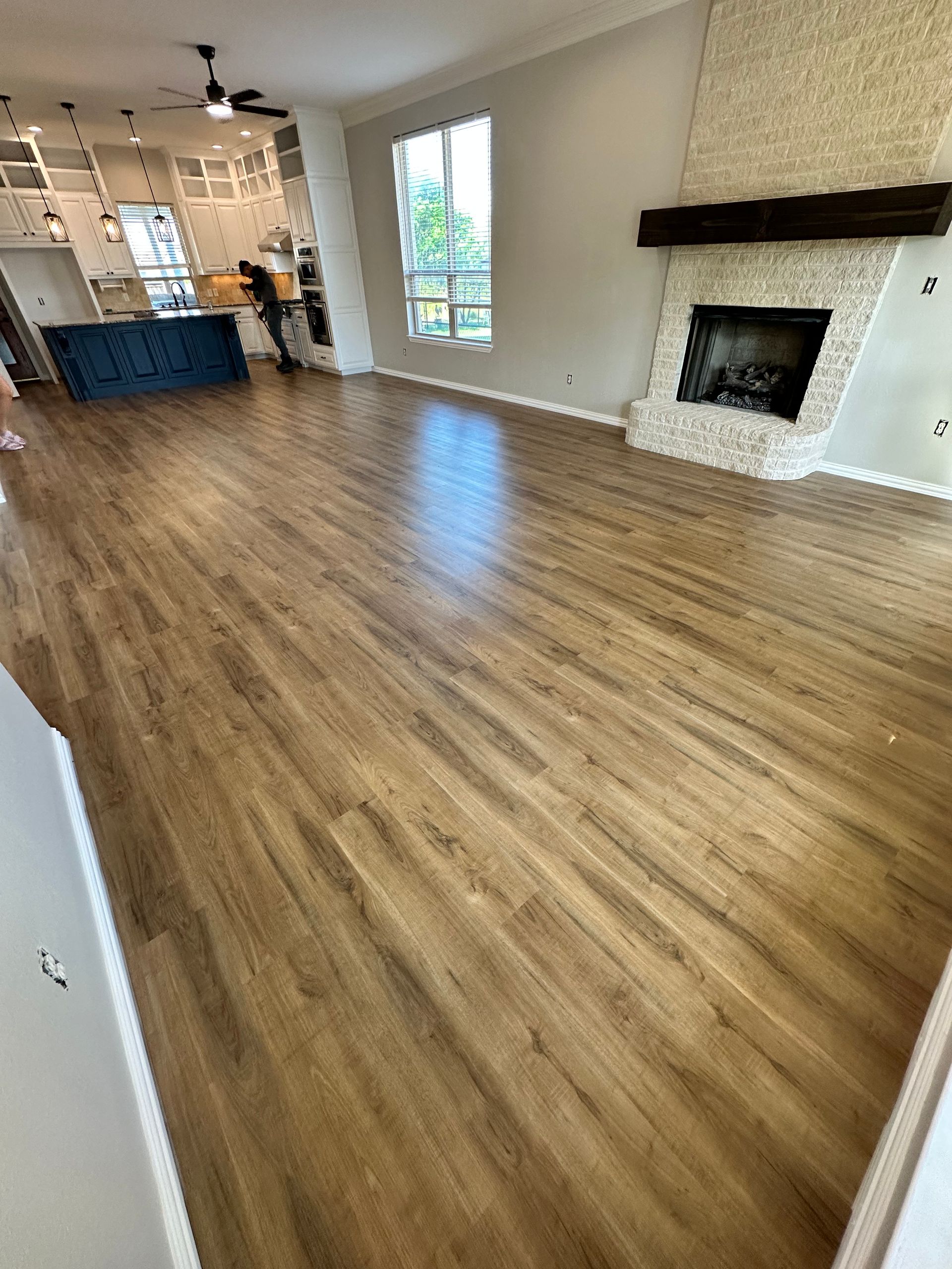 Living room with wood flooring, a fireplace, and a view of the kitchen.