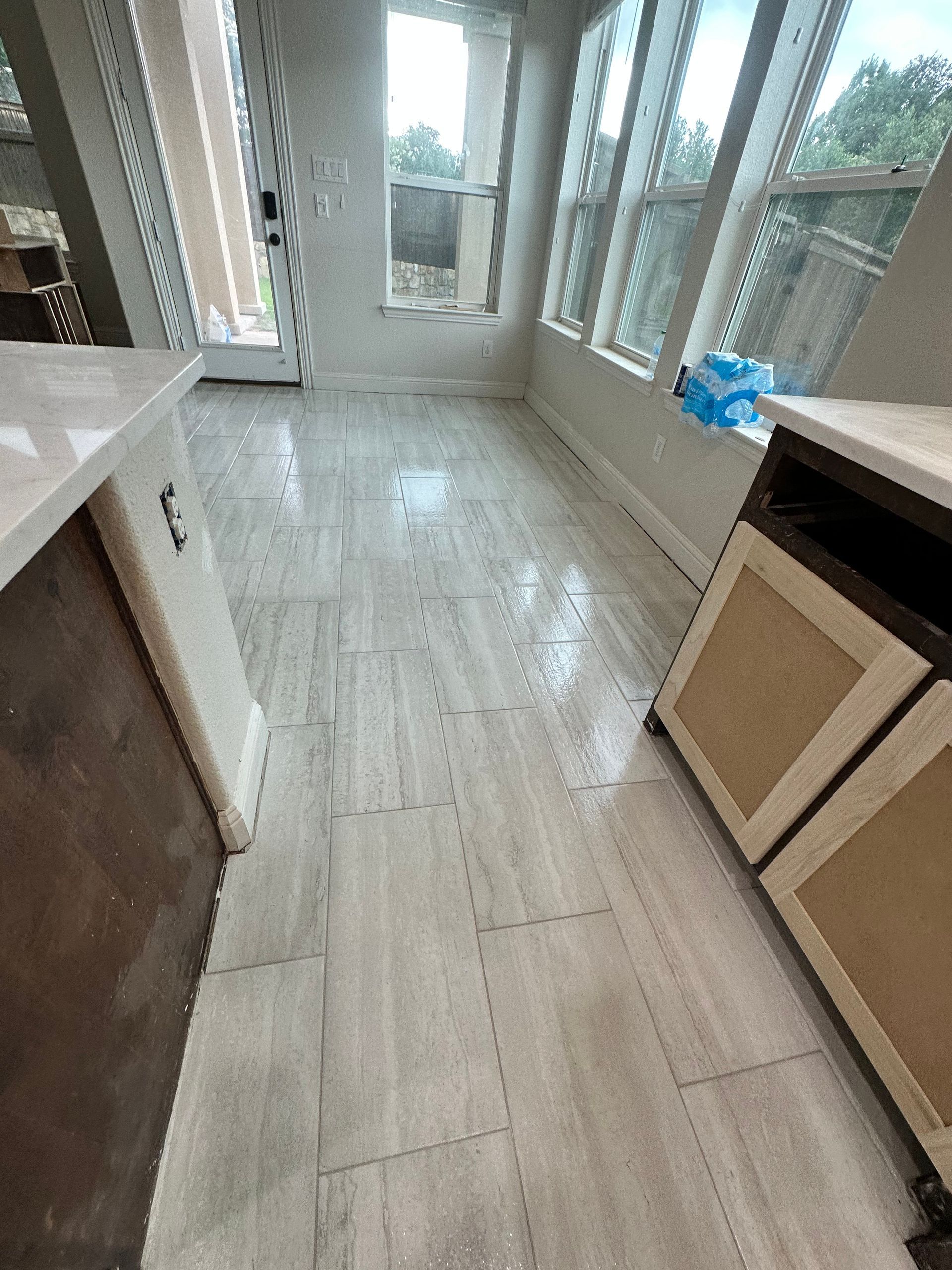 Kitchen with light gray tile floor and cabinets. Windows and countertops are also visible.
